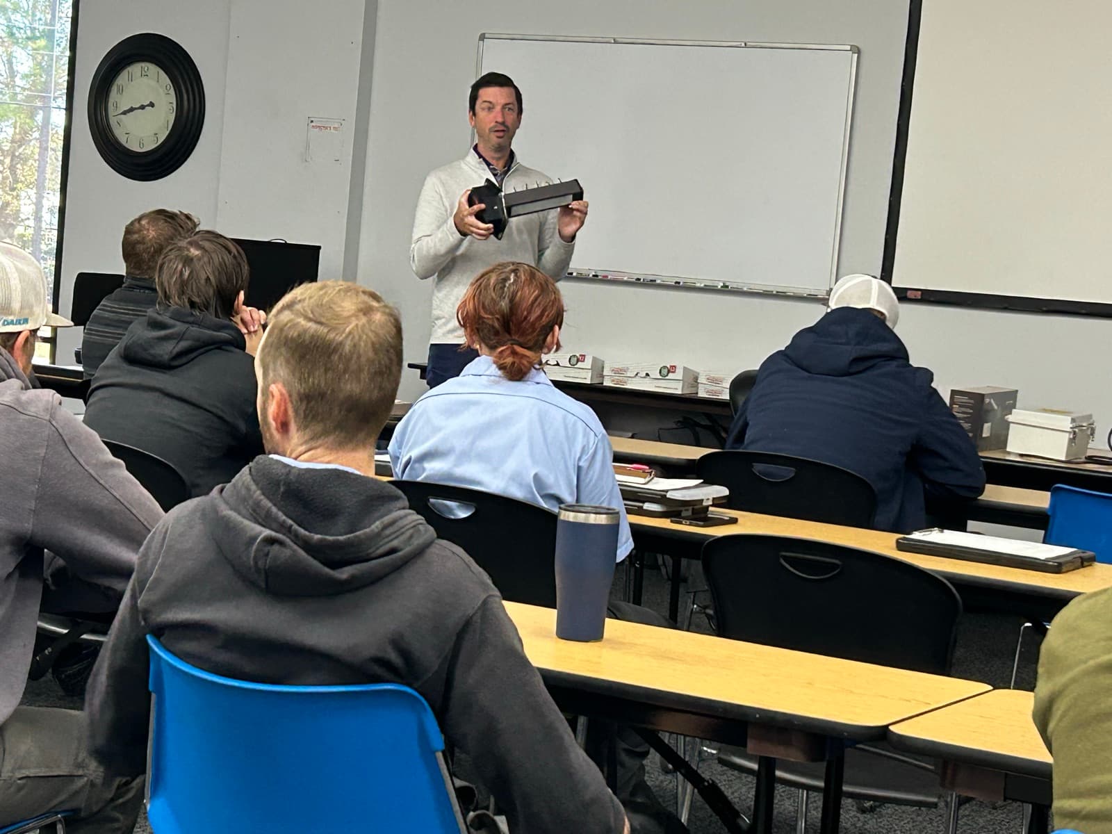 Rep holding up a tool in front of a training group